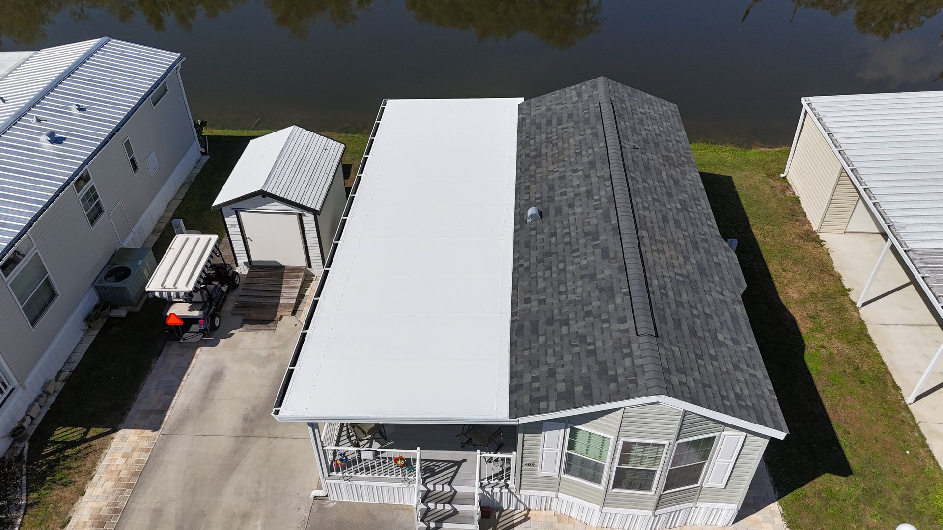 An aerial view of a mobile home in a mobile home park next to a body of water.