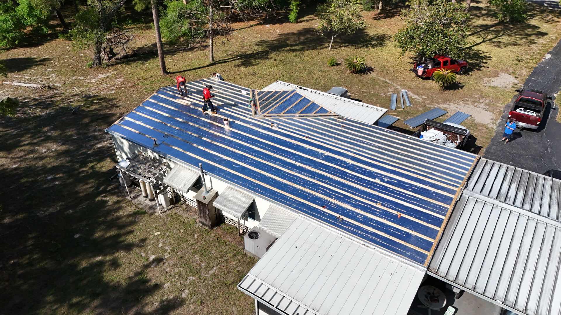 An aerial view of a house being remodeled with solar panels on the roof.