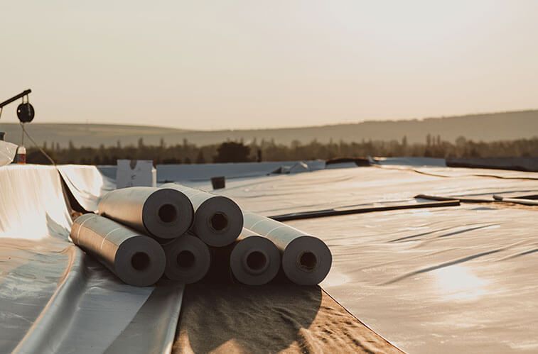 A stack of rolls of roofing material sitting on top of a roof.