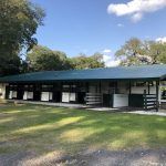A large building with a blue roof is surrounded by trees and grass.