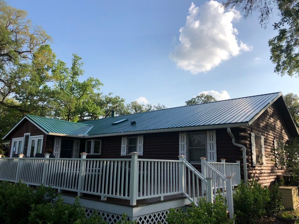 A house with a green roof and a white deck