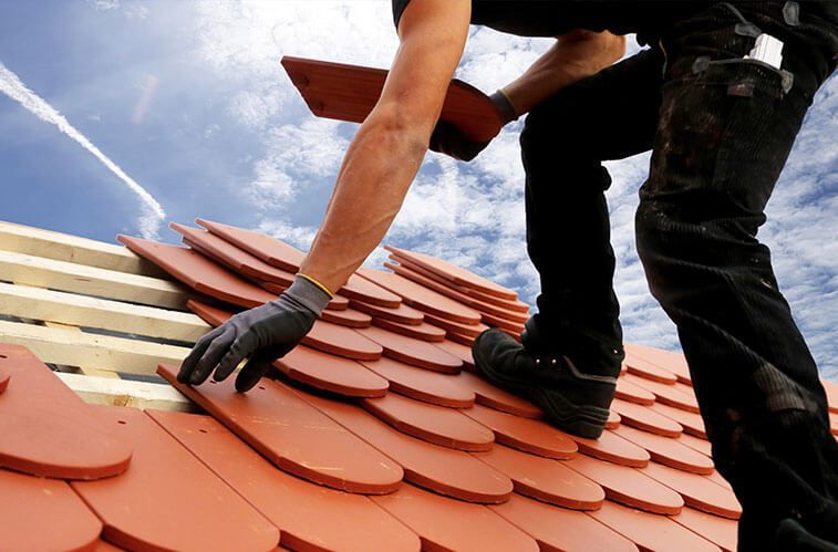 A man is working on a roof with red tiles