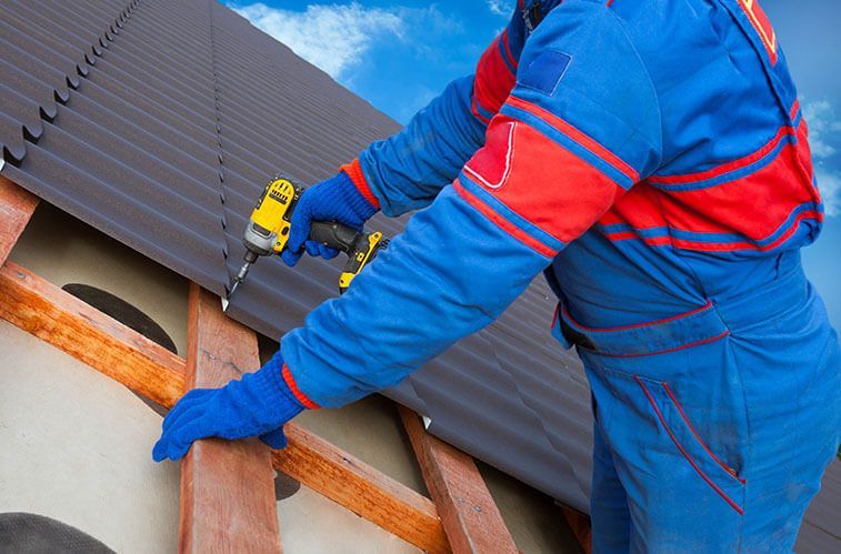 A man is working on a roof with a drill.