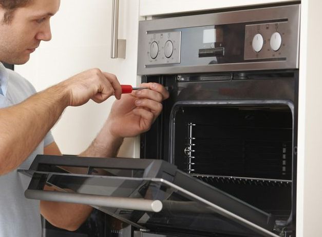 Man Repairing Domestic Oven In Kitchen —  Townsville Electrical and Appliance Repairs In Garbutt QLD