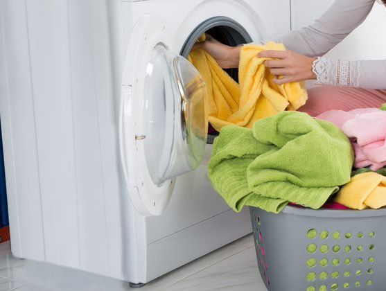 Woman Putting Clothes In The Washing Machine Appliances — Townsville Electrical and Appliance Repairs In Garbutt QLD