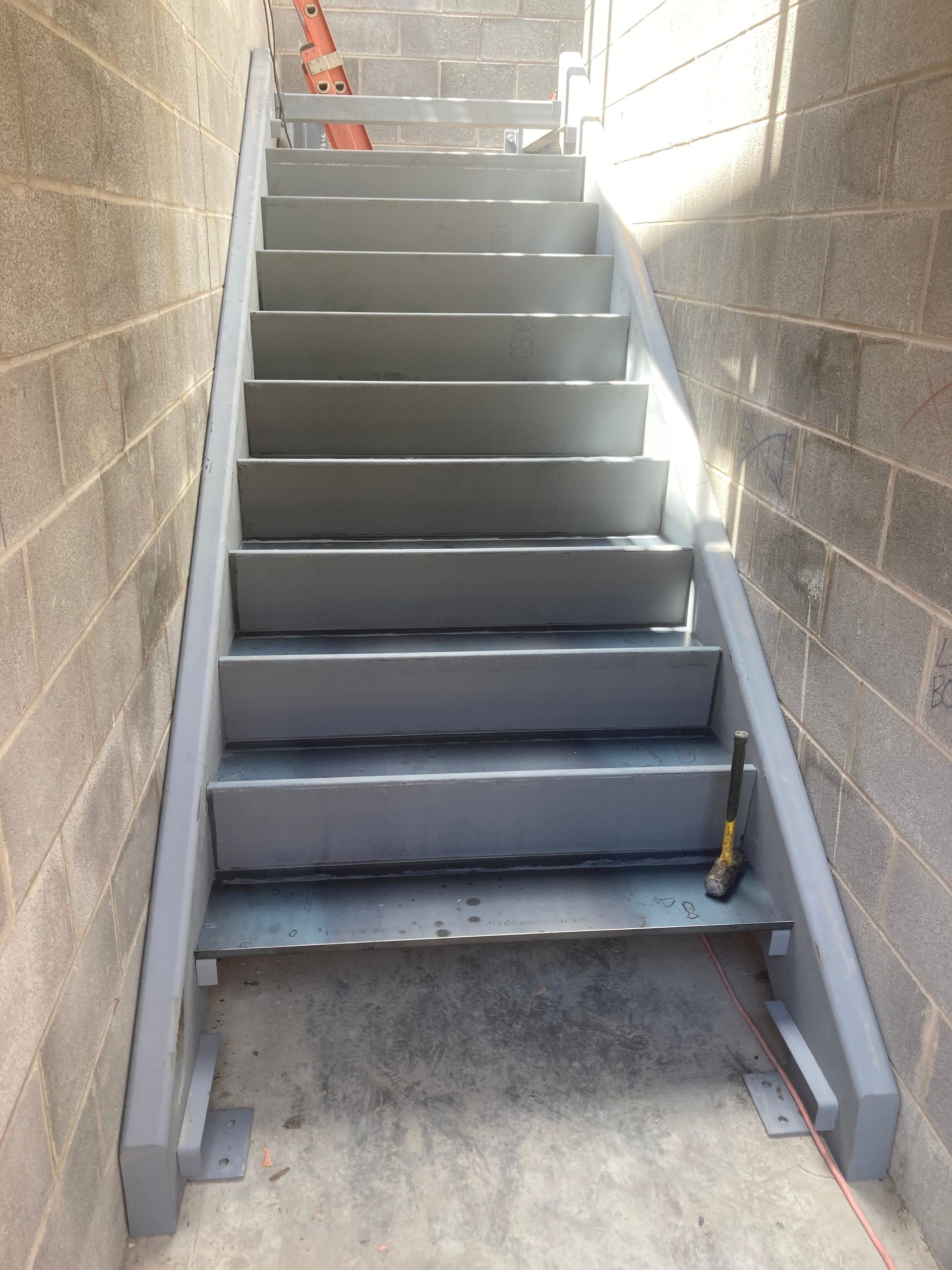 Gray metal stairs between gray brick walls.