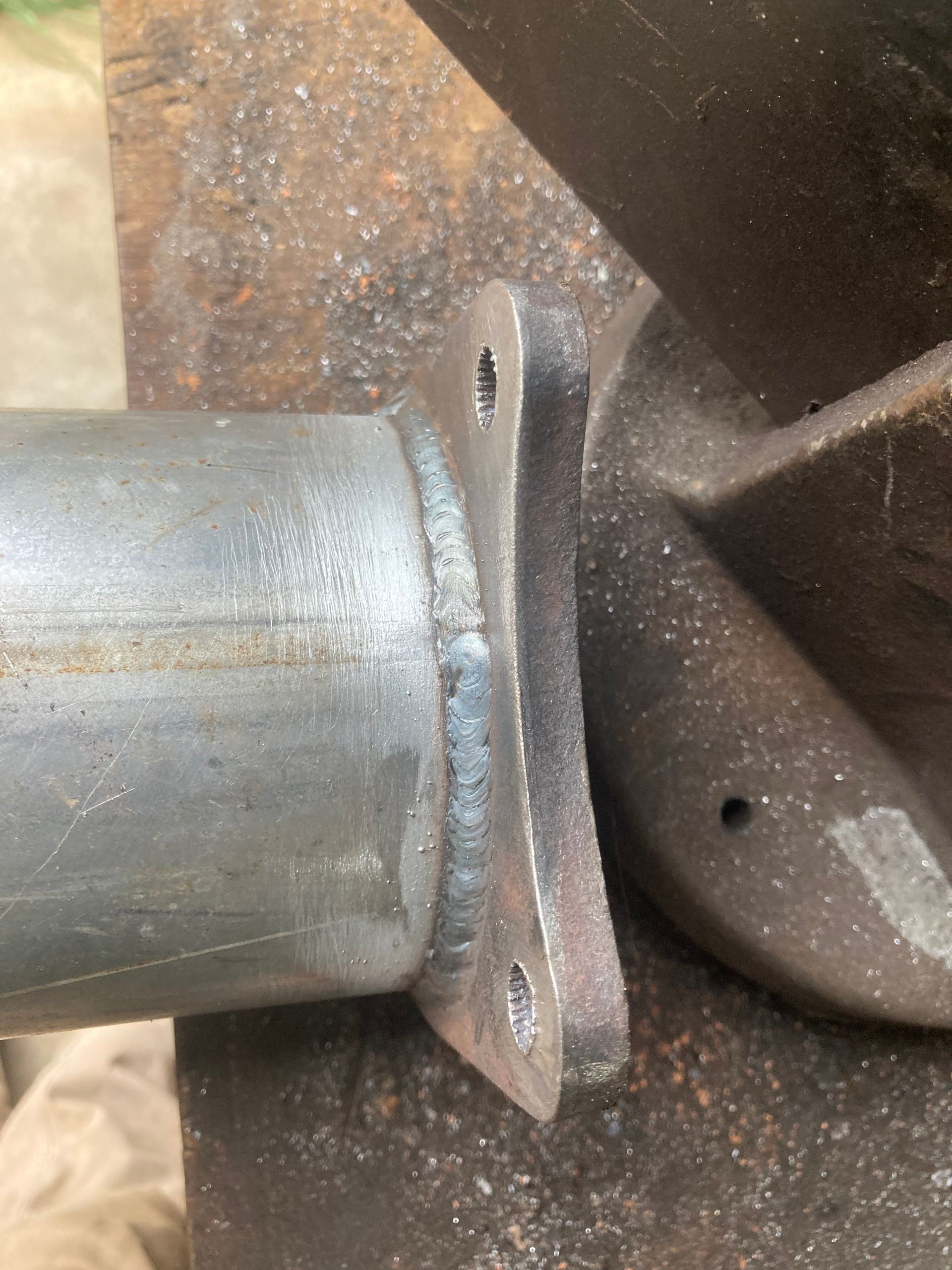 Metal pipe with welded flange attached to a dark surface.