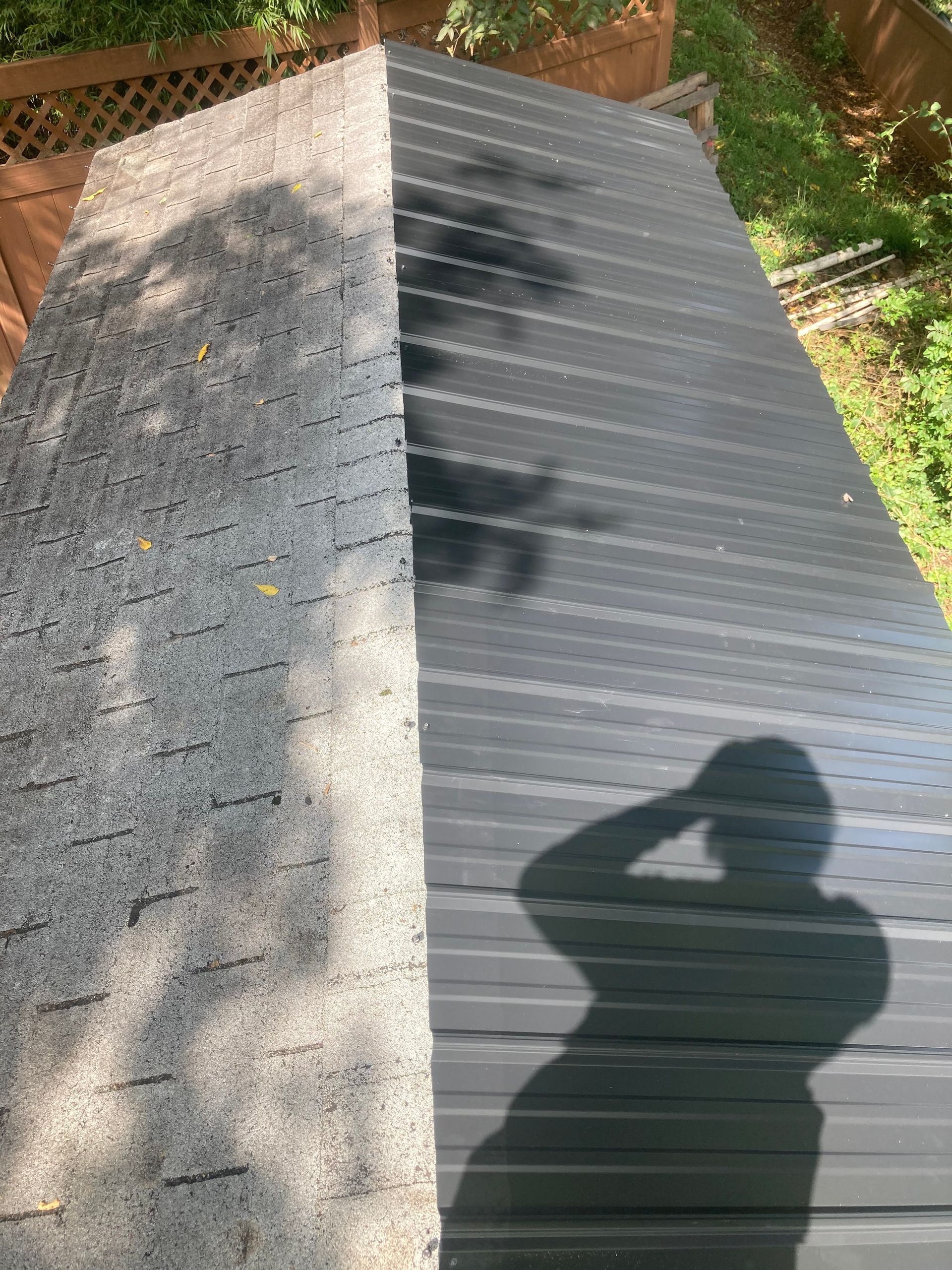 Comparison of a shed roof: left side is gray asphalt shingles, right side is dark metal.