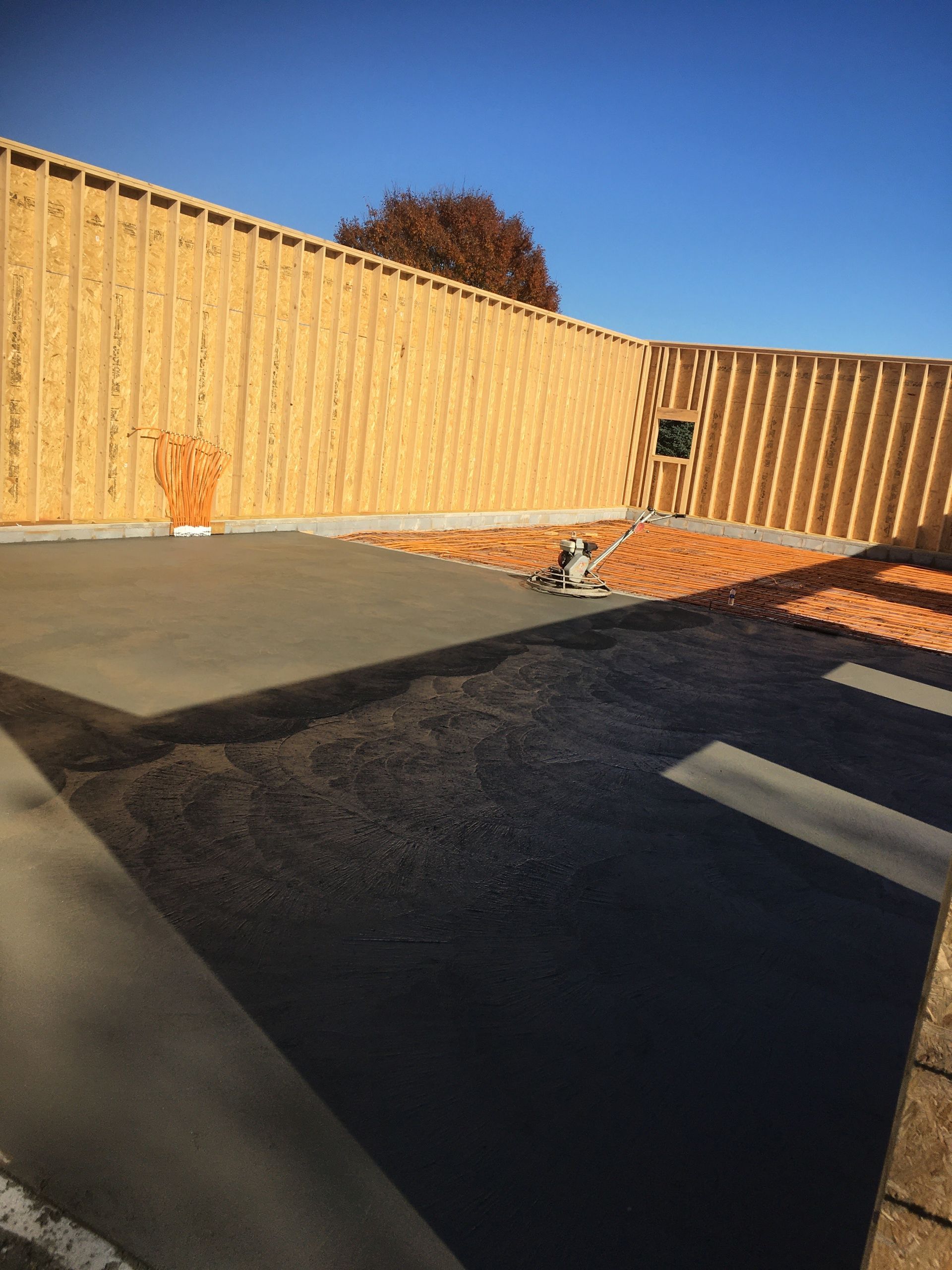 New concrete patio with wooden framing under a blue sky.