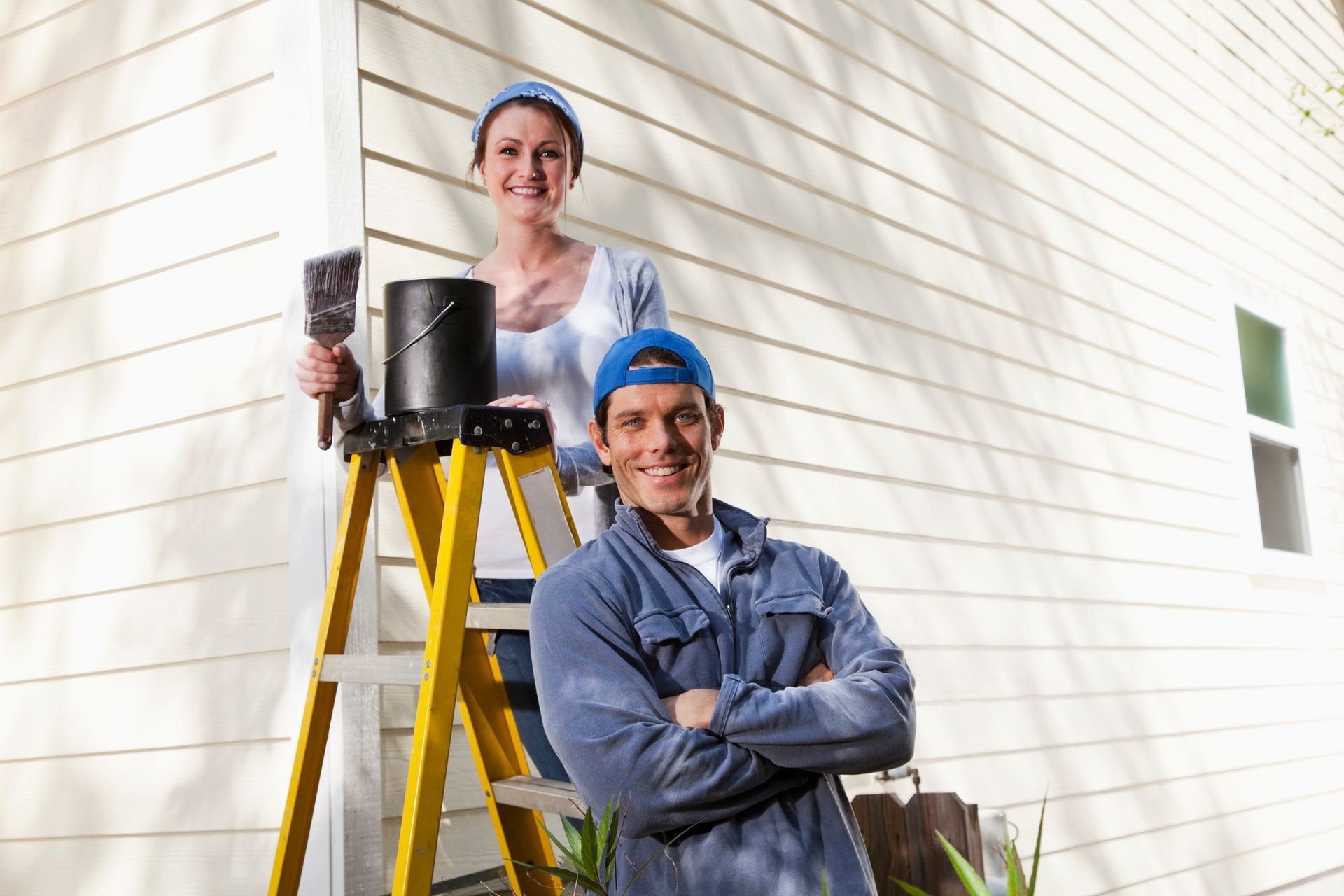 Couple doing home maintenance project outside house