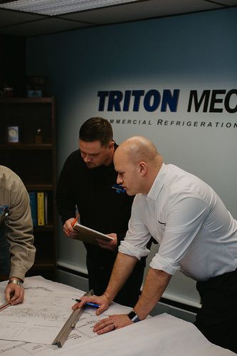 A group of men are looking at a blueprint on a table.
