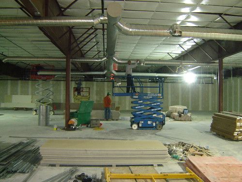 A man is standing on a scissor lift in a warehouse.