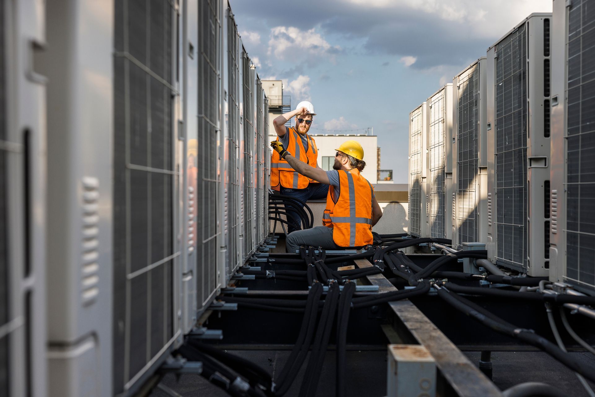 Two construction workers are working on the roof of a building.