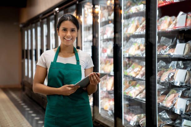 Portrait of a retail clerk in front of commercial refrigeration.