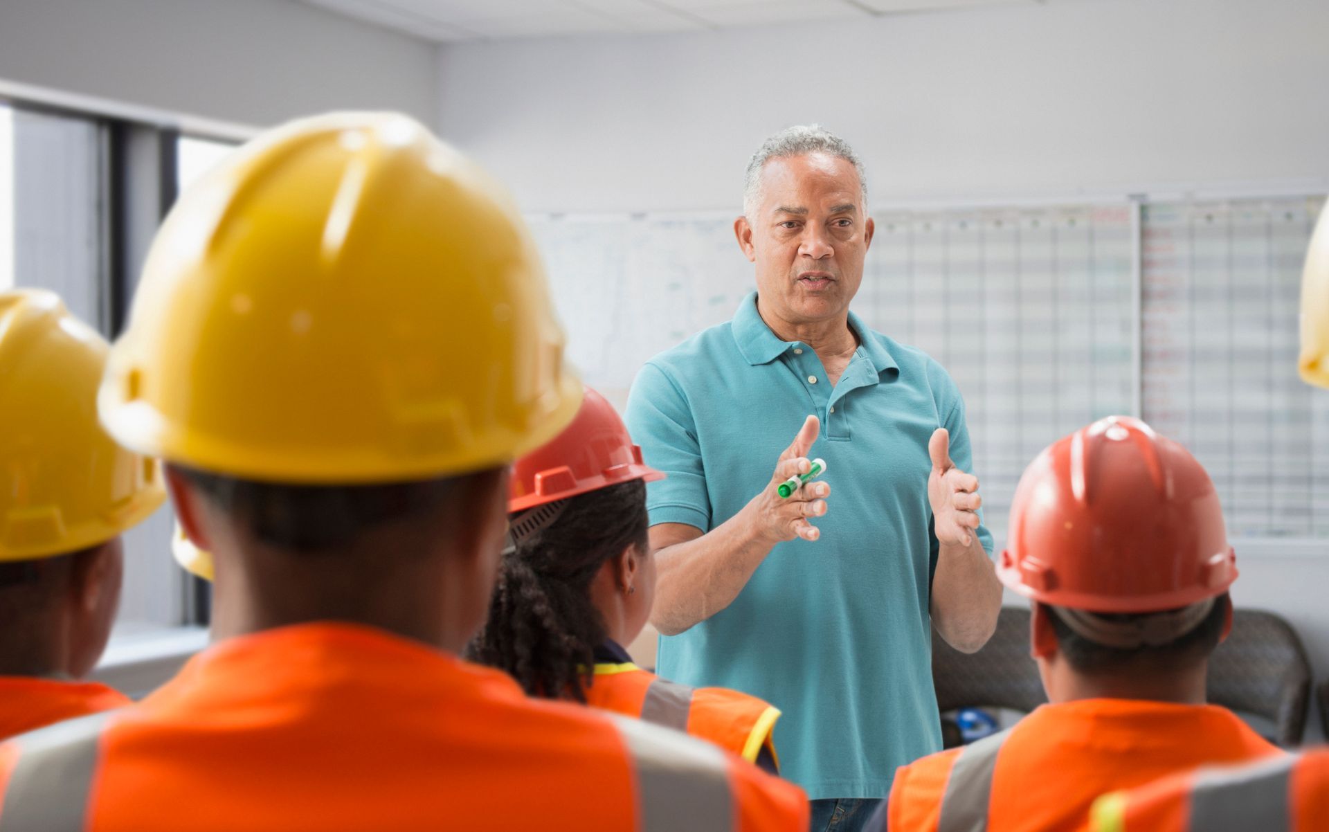 A man is giving a presentation to a group of construction workers.