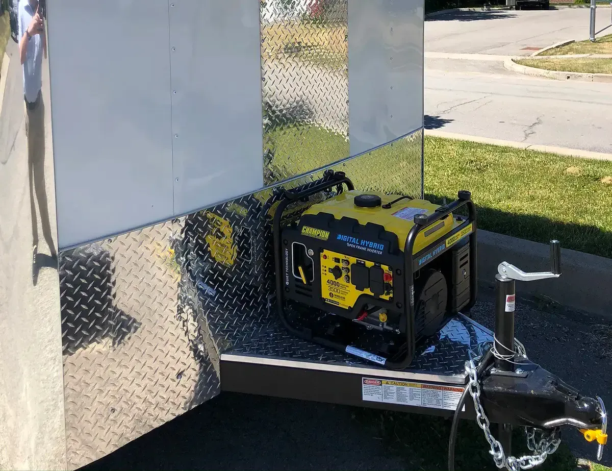 A yellow generator is attached to the back of a trailer.