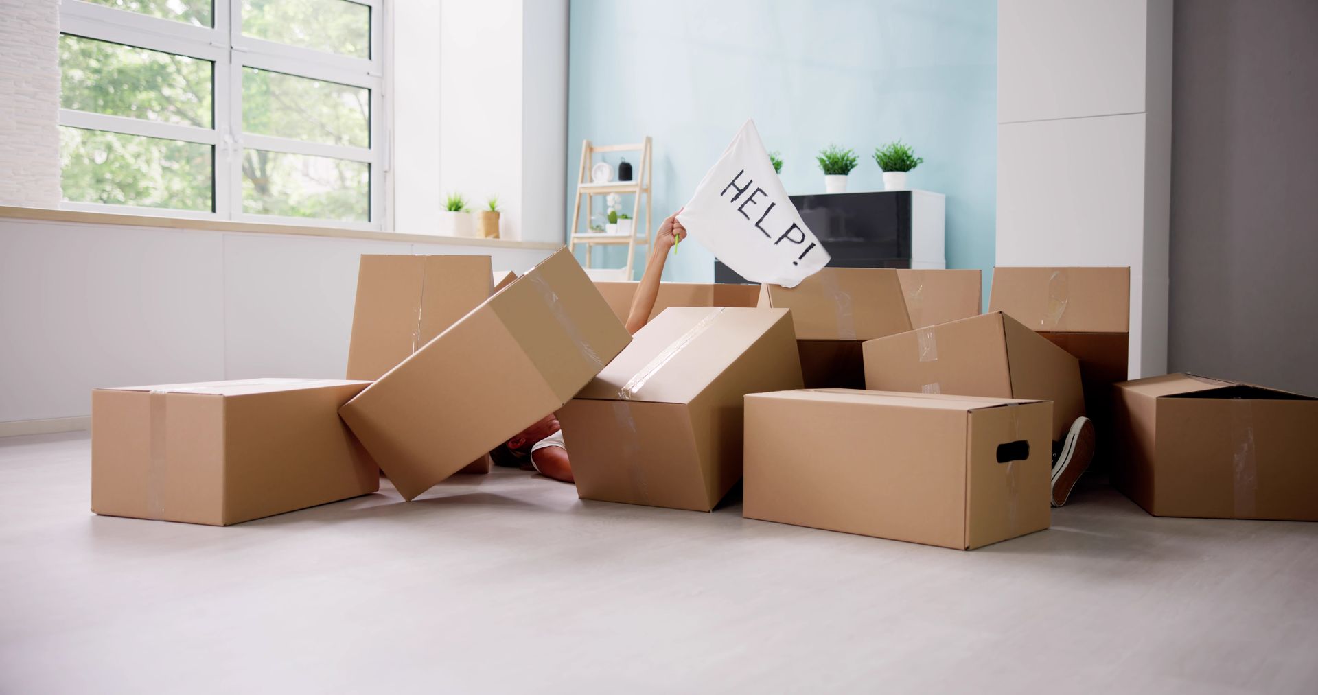 A person overwhelmed by moving boxes and waving a white flag