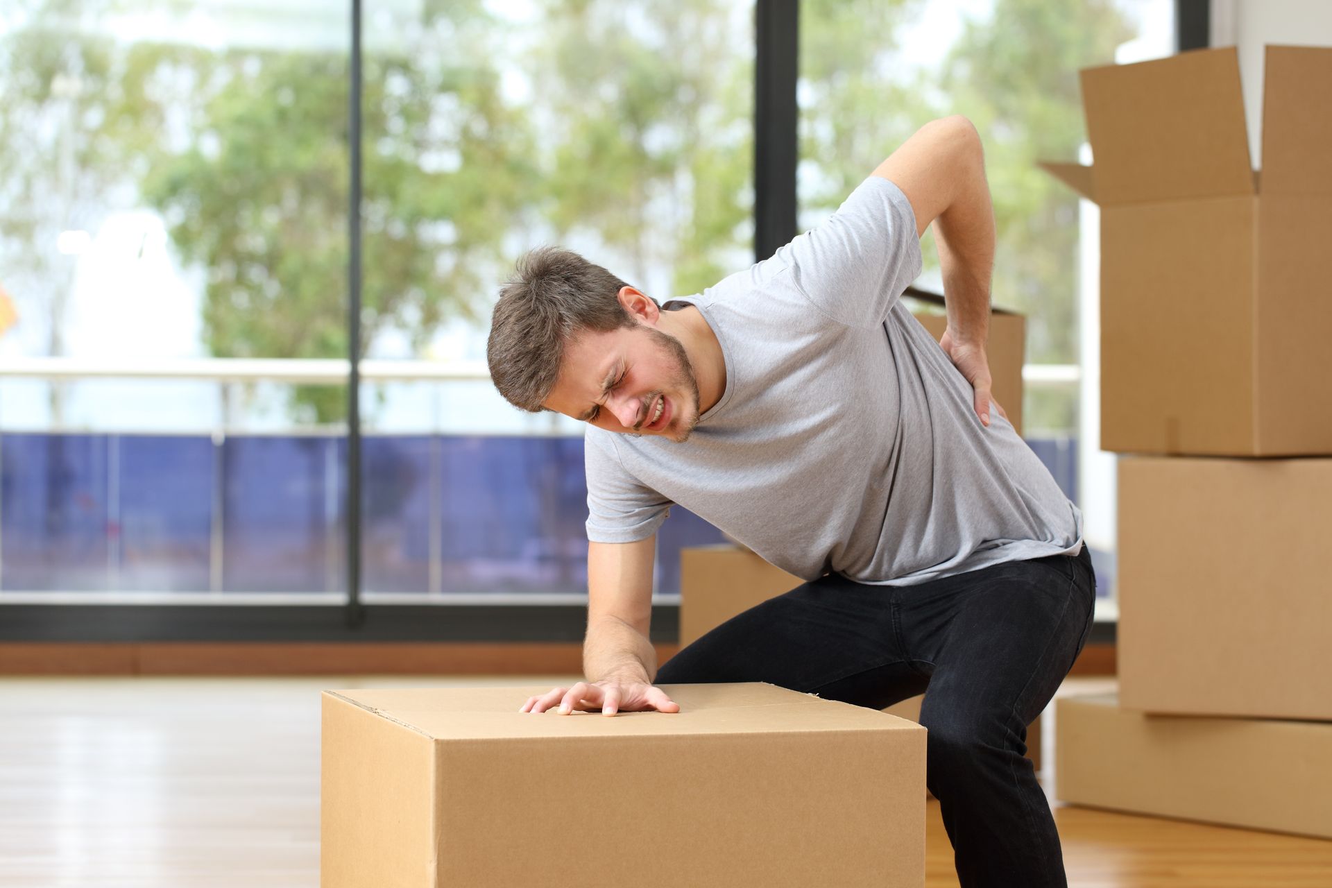 Young man experiencing a back injury after trying to move a box by himself.