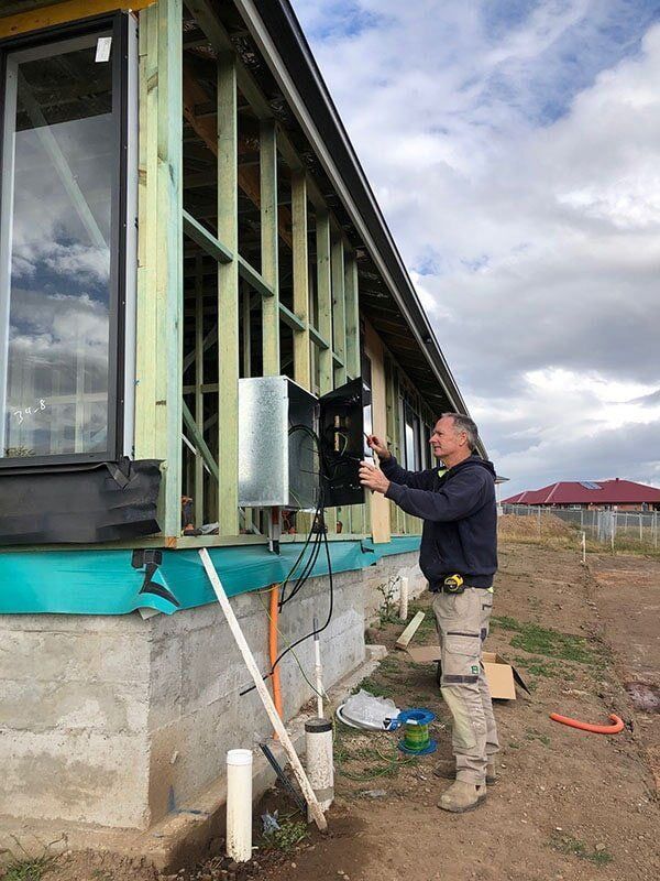 A Man Is Standing In Front Of A Building Under Construction — EESI Electrical Contractors In Alstonville, NSW