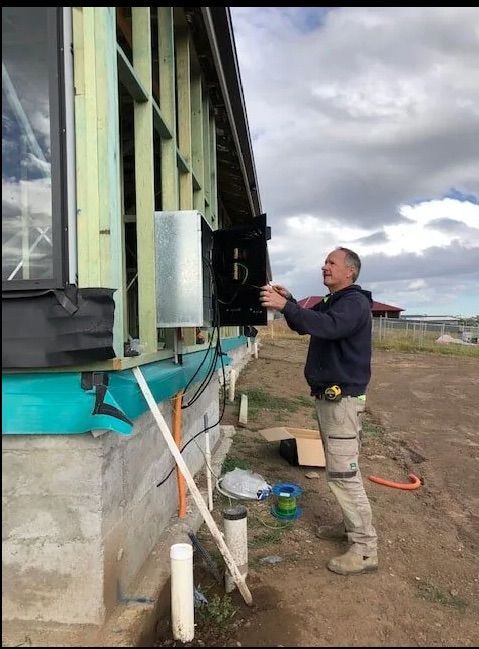 A Man Is Working On An Electrical Box With A Screwdriver — EESI Electrical Contractors In Alstonville, NSW