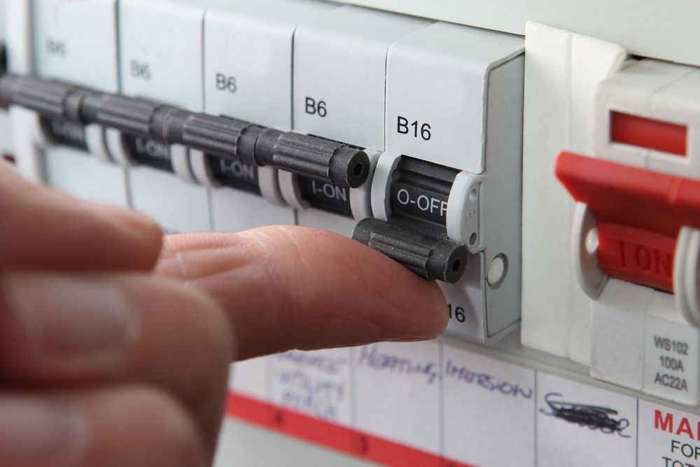 A Person Is Pressing A Button On A Circuit Breaker — EESI Electrical Contractors In Alstonville, NSW