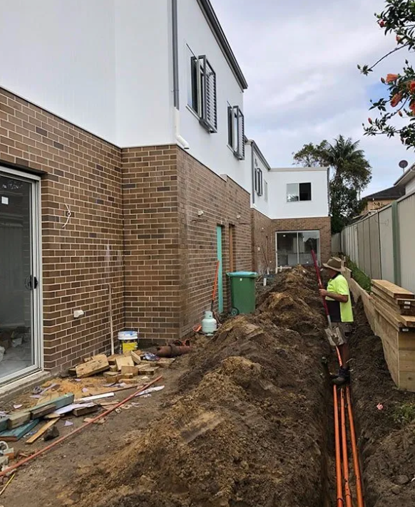 A Person Is Working On An Electrical trench holding a Spade — EESI Electrical Contractors In Alstonville, NSW