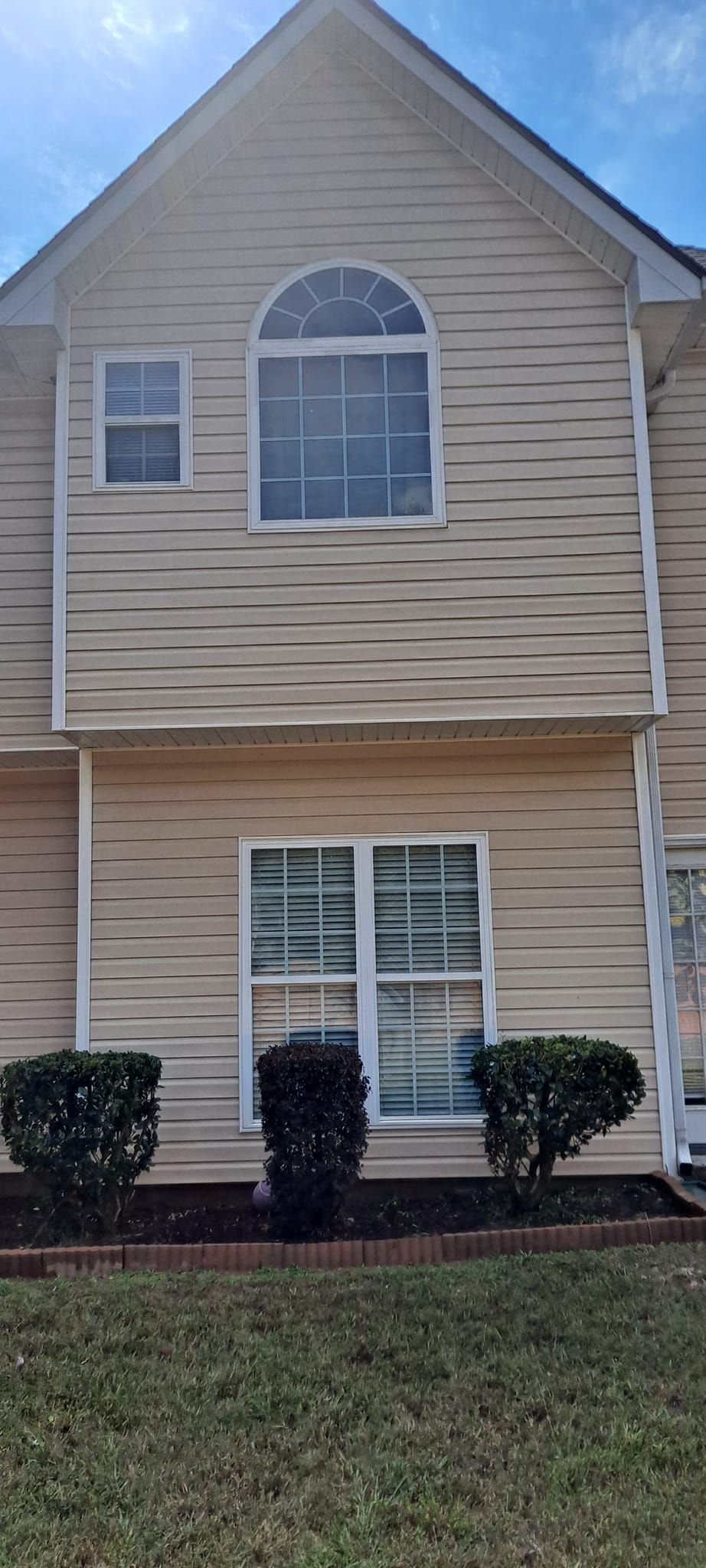 A house with a lot of windows and bushes in front of it.