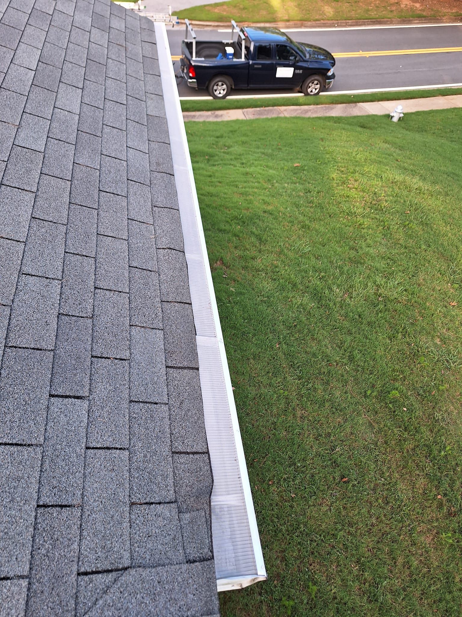 A truck is parked on the side of a house next to a gutter.