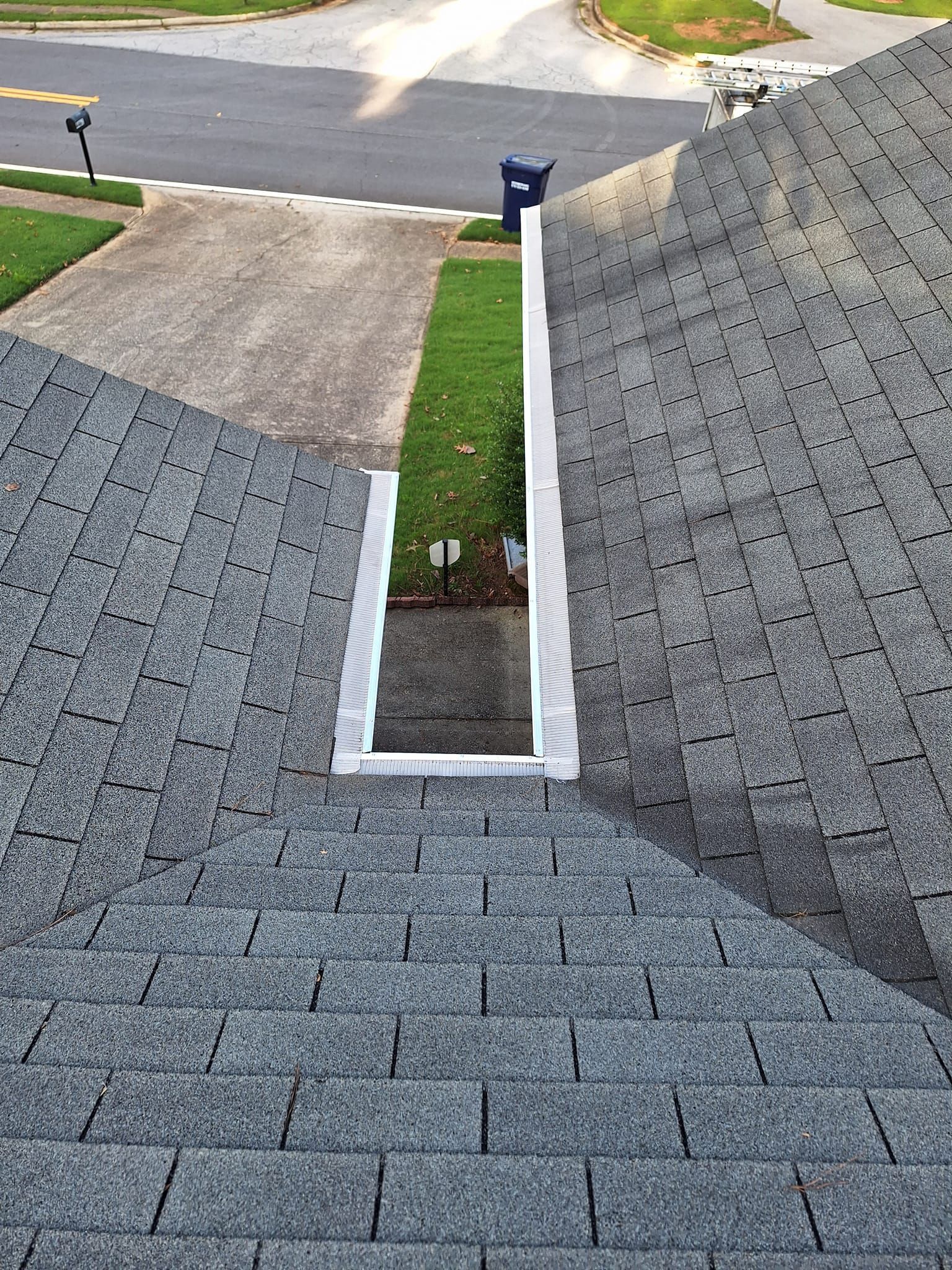 A roof with a hole in it and a mailbox in the background.