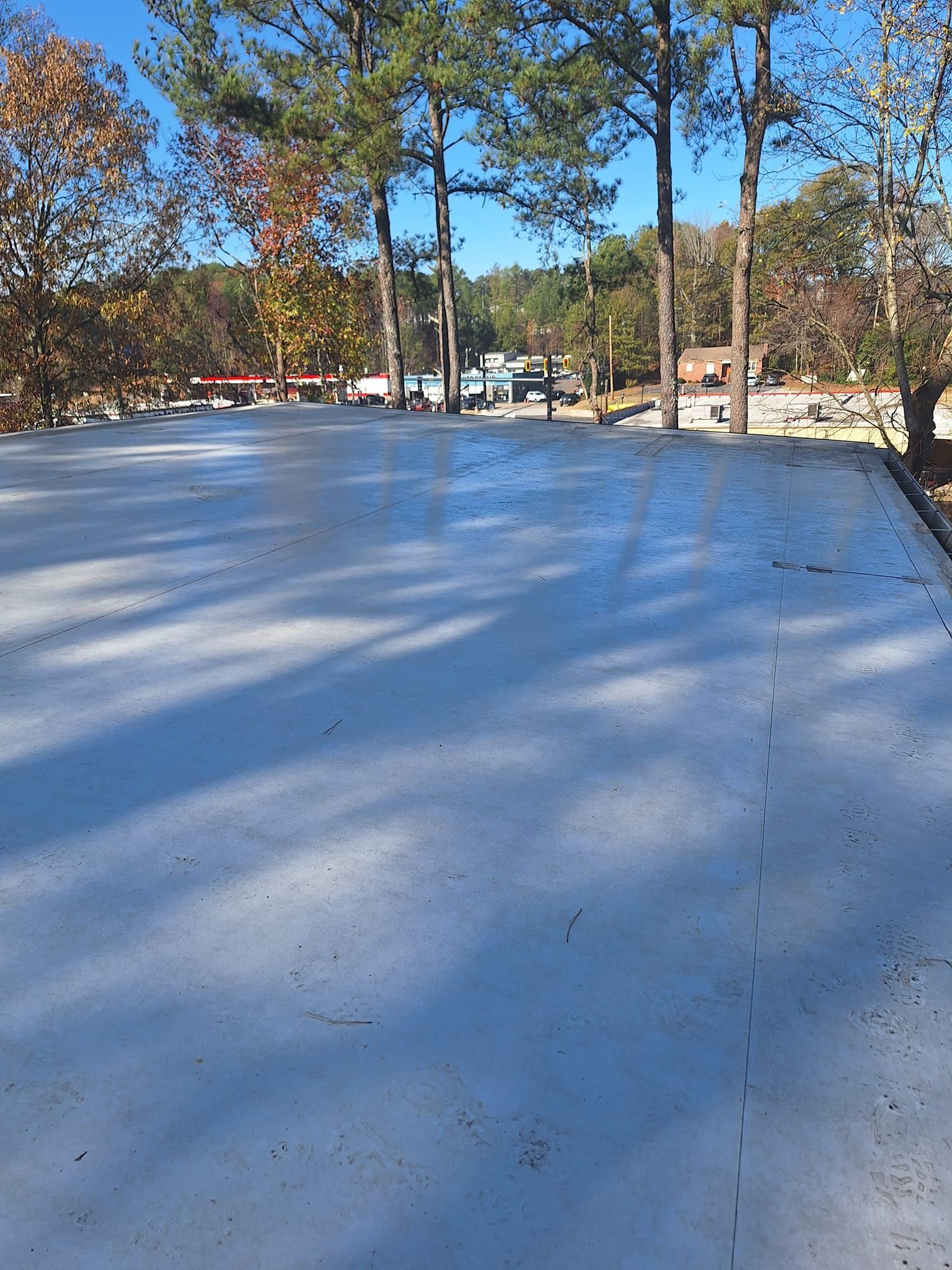 A concrete driveway with trees in the background on a sunny day.