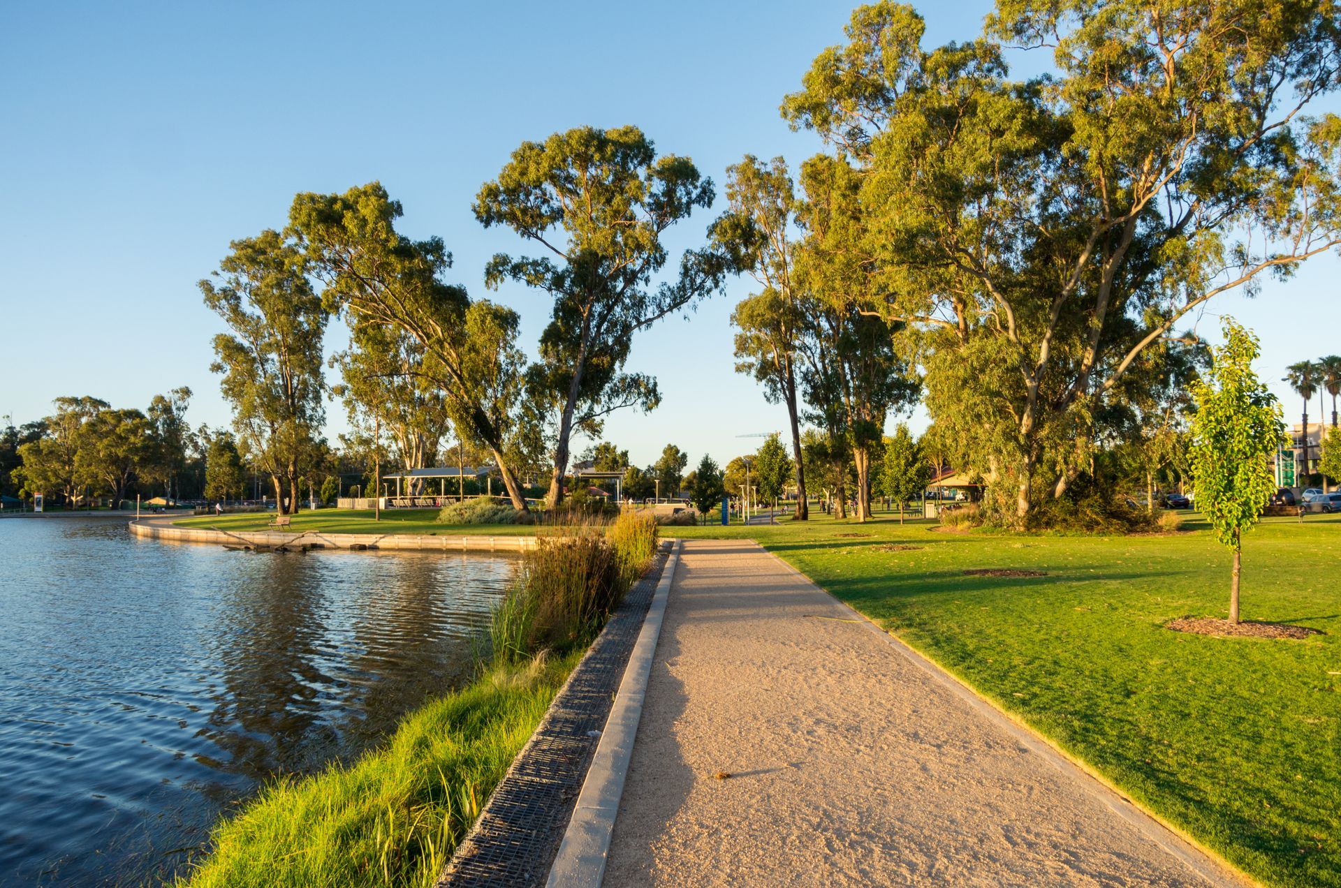 Pathway along a lake with green grass, trees, and blue sky — JSF Interiors Goulburn in Goulburn, NSW