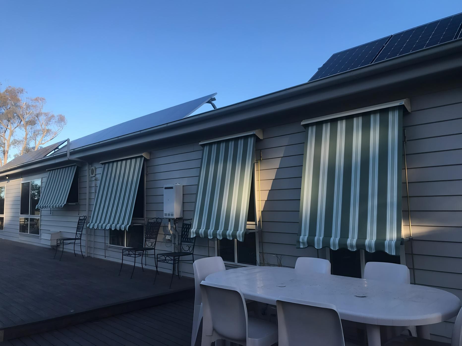 House exterior with striped awnings, solar panels, and a deck with outdoor furniture — JSF Interiors Goulburn in Goulburn, NSW