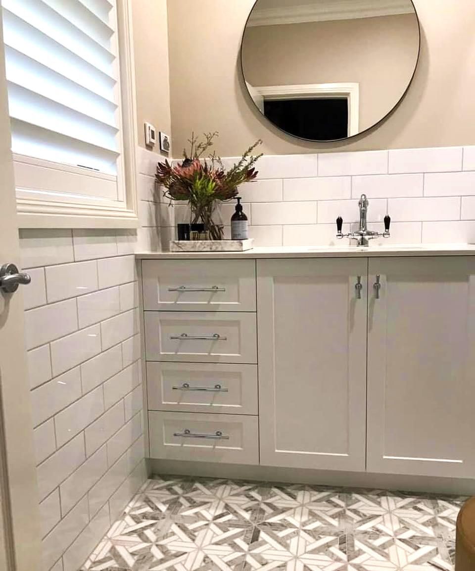 White Bathroom With Vanity, Round Mirror, Patterned Floor, And Flowers — JSF Interiors Goulburn in Gerringong, NSW