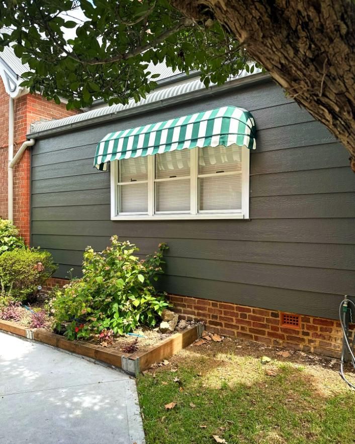 Green And White Striped Awning Over Window On Gray House — JSF Interiors Goulburn in Bowral, NSW