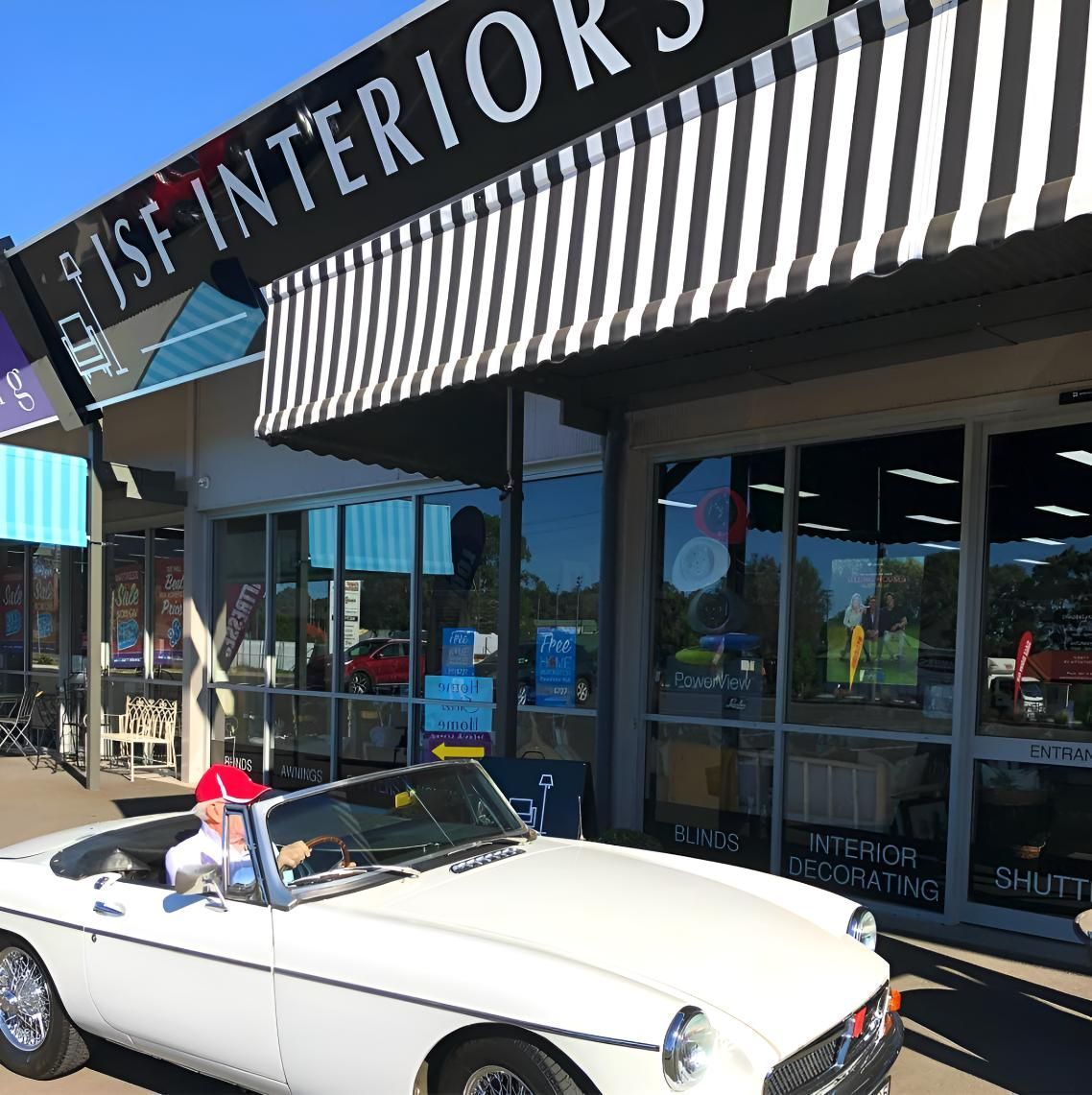 White Convertible Car In Front Of Store With Striped Awning — JSF Interiors Goulburn In Kiama, NSW
