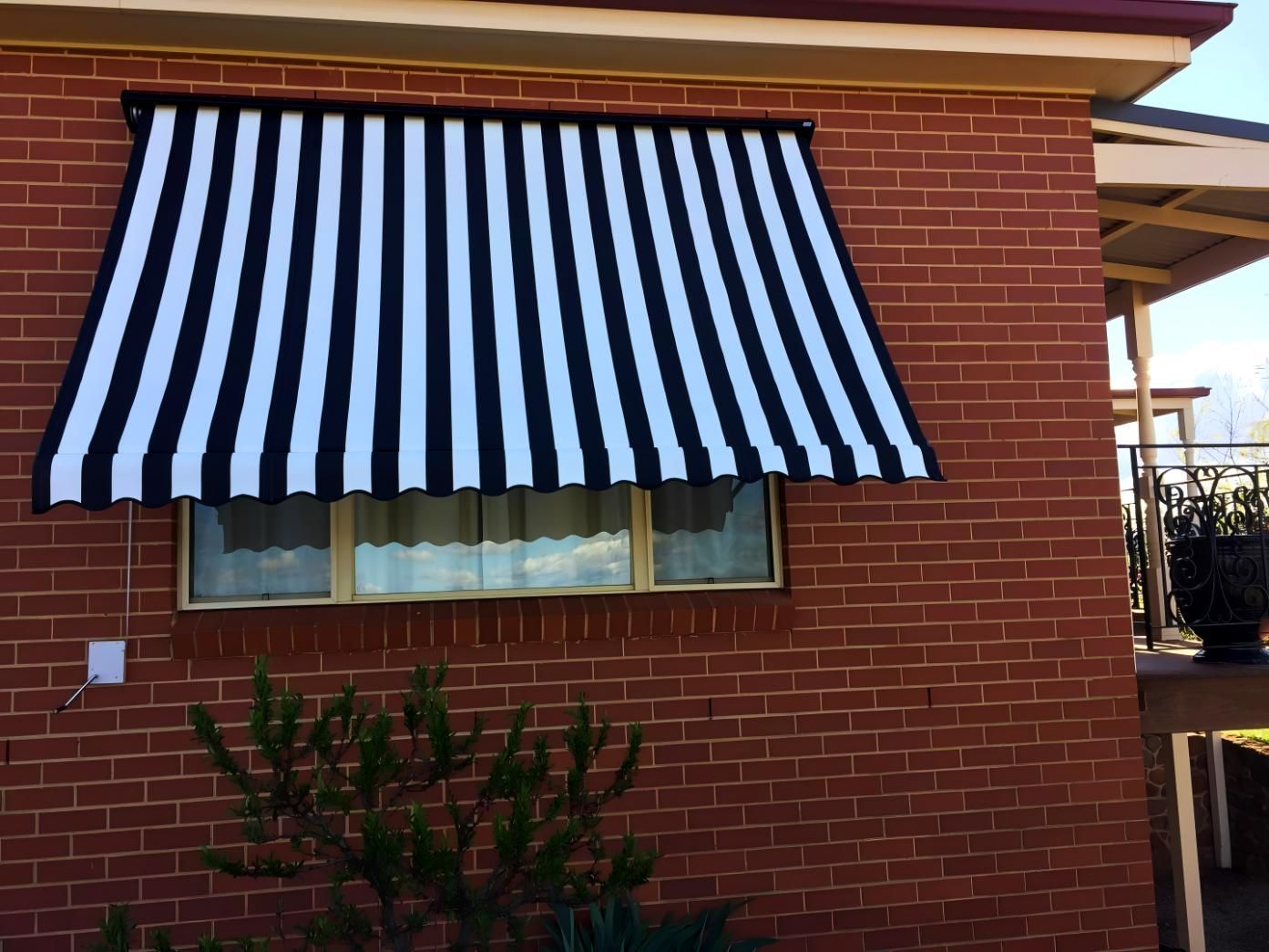 Black And White Striped Awning On Red Brick Building — JSF Interiors Goulburn in Wollongong, NSW