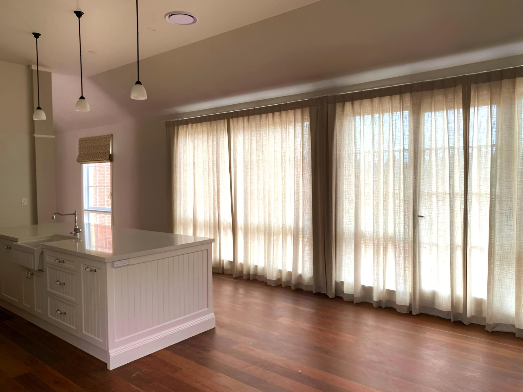 Spacious Kitchen With White Island, Wooden Floors, And Sheer Beige Curtains — JSF Interiors Goulburn In Kiama, NSW