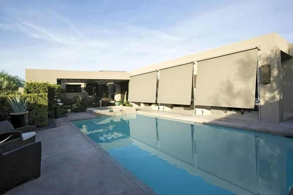 A rectangular pool reflects the blue sky and a modern home with retractable shades — JSF Interiors Goulburn in Goulburn, NSW