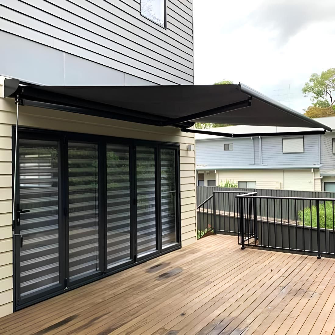 Black Awning Extended Over Patio Doors on Wooden Deck — JSF Interiors Goulburn in Wollongong, NSW