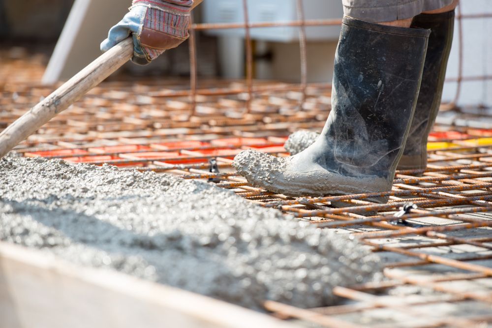 A concrete floor is being built in a backyard next to a green fence.