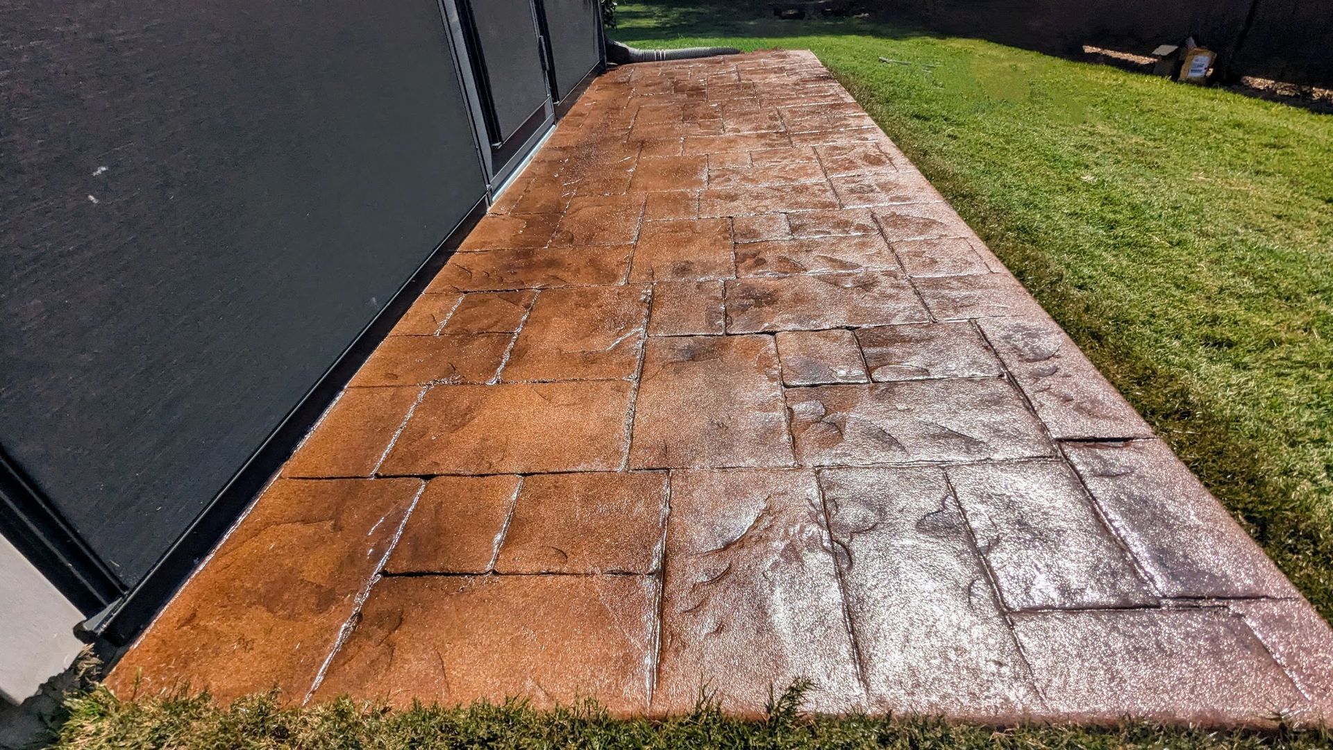 A black pool cover is sitting on top of a patio next to a swimming pool.