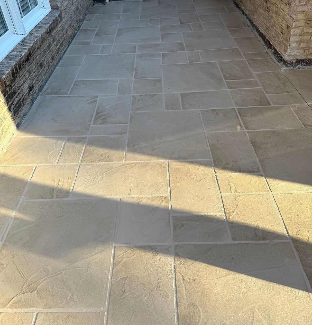 A concrete walkway with a curb and bushes on the side.