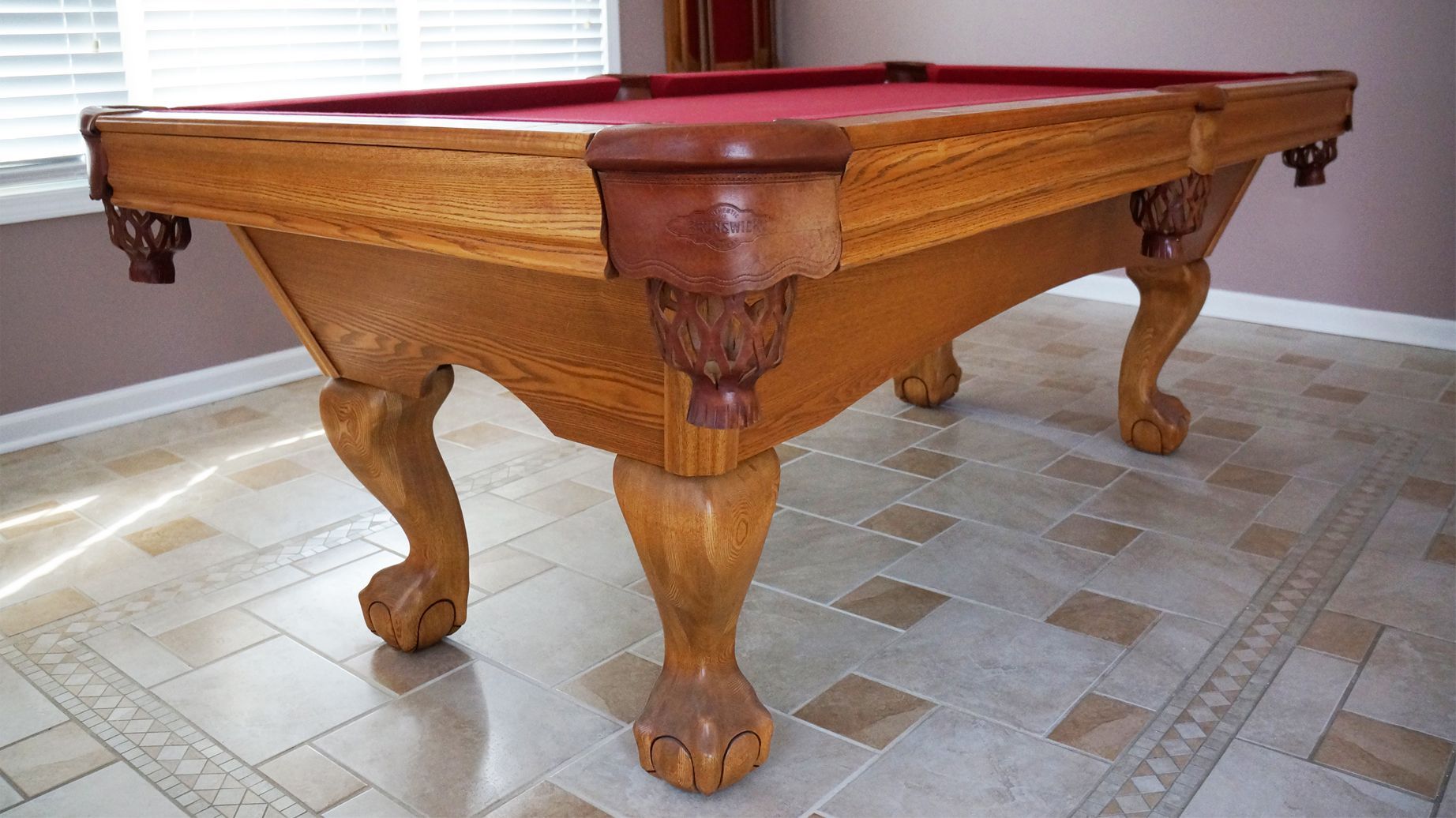 A pool table is sitting on a tiled floor in a room.