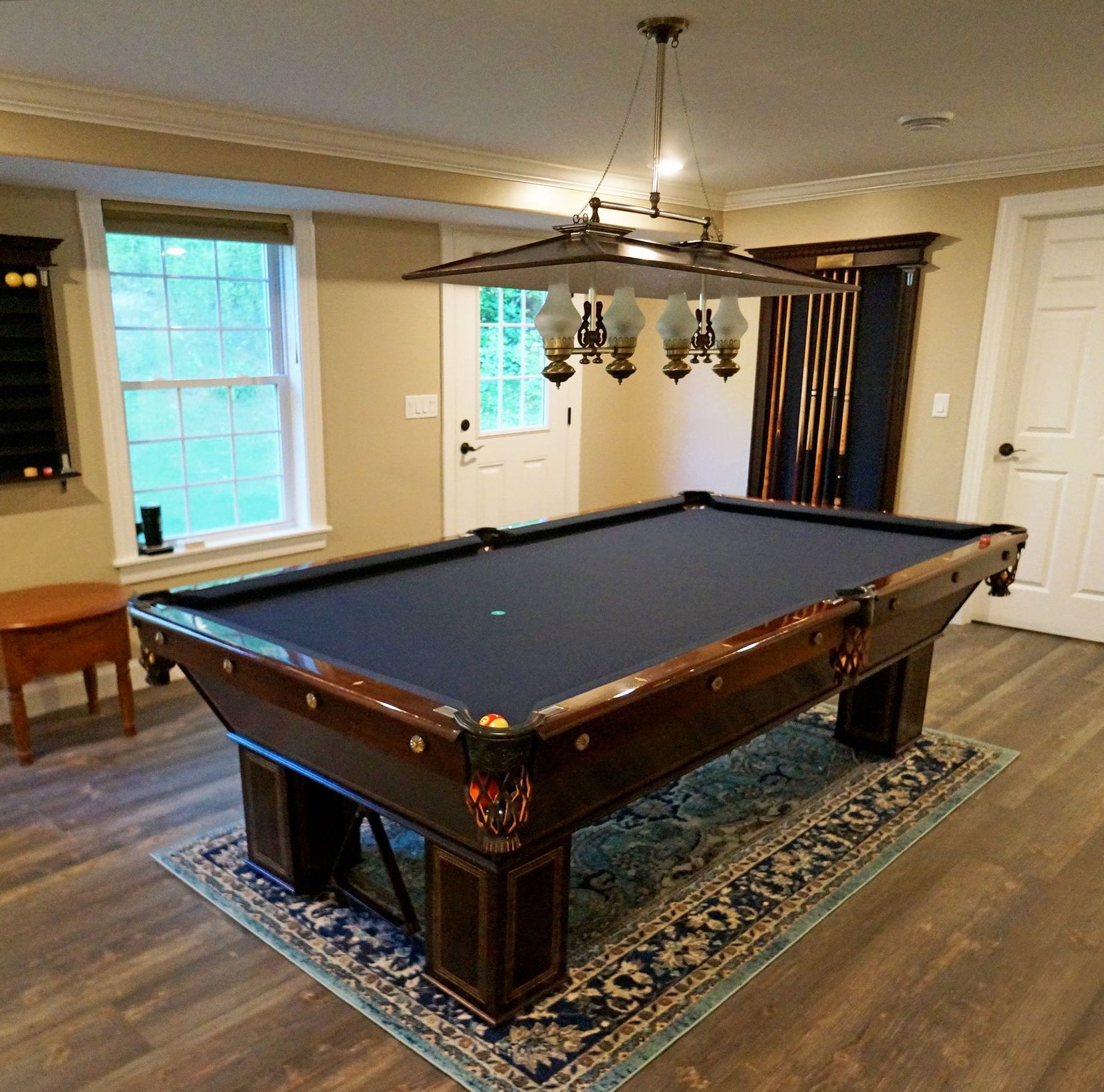 A pool table in a room with a chandelier hanging from the ceiling