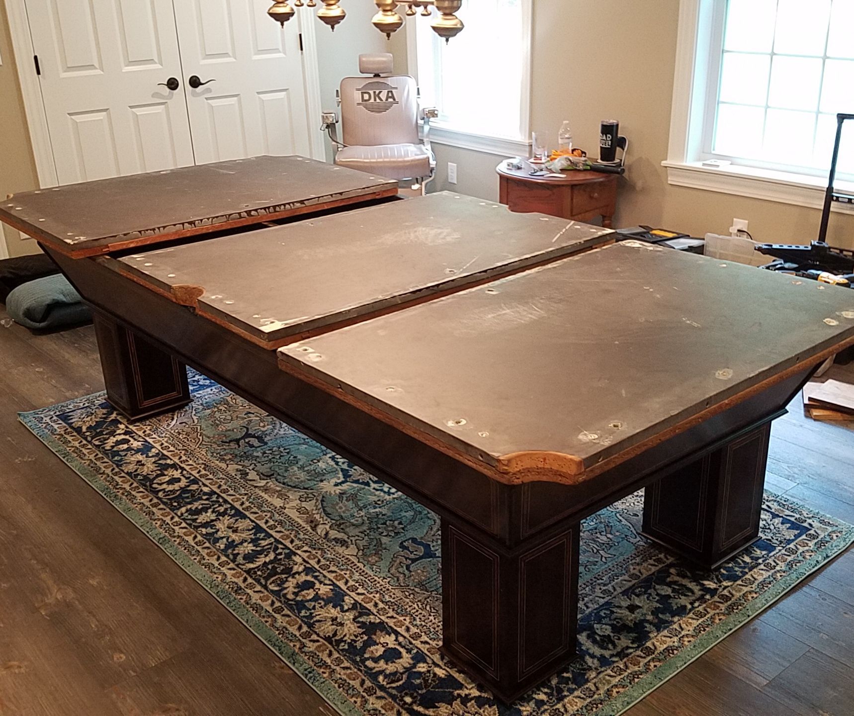 A pool table is sitting on a rug in a room next to a window.