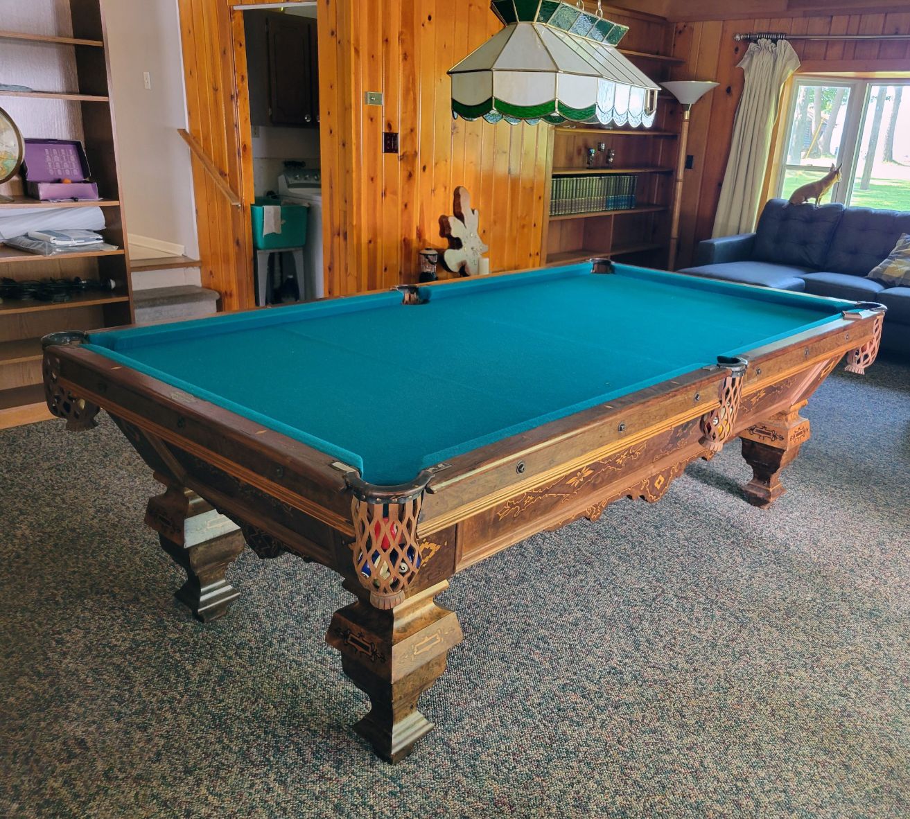 A pool table in a living room next to a couch