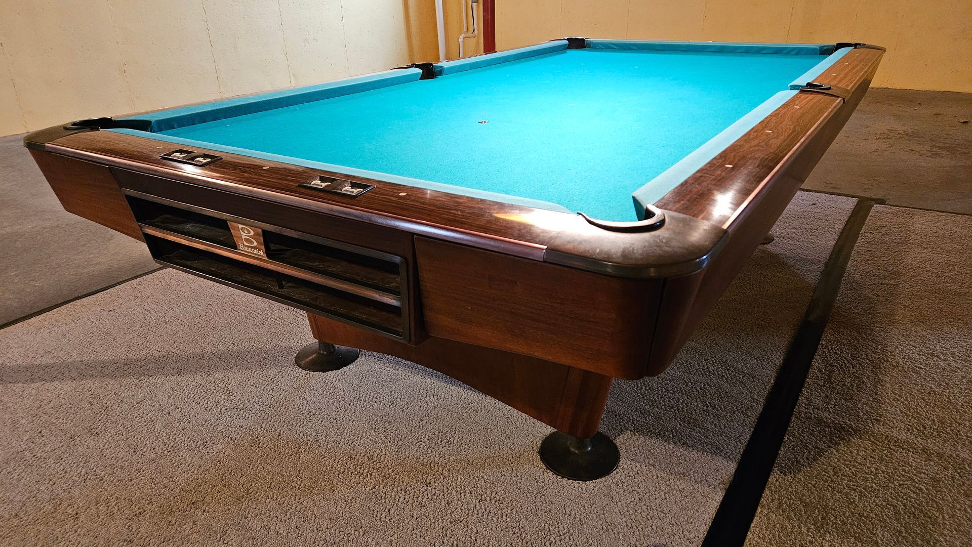 A pool table is sitting on a carpeted floor in a room.