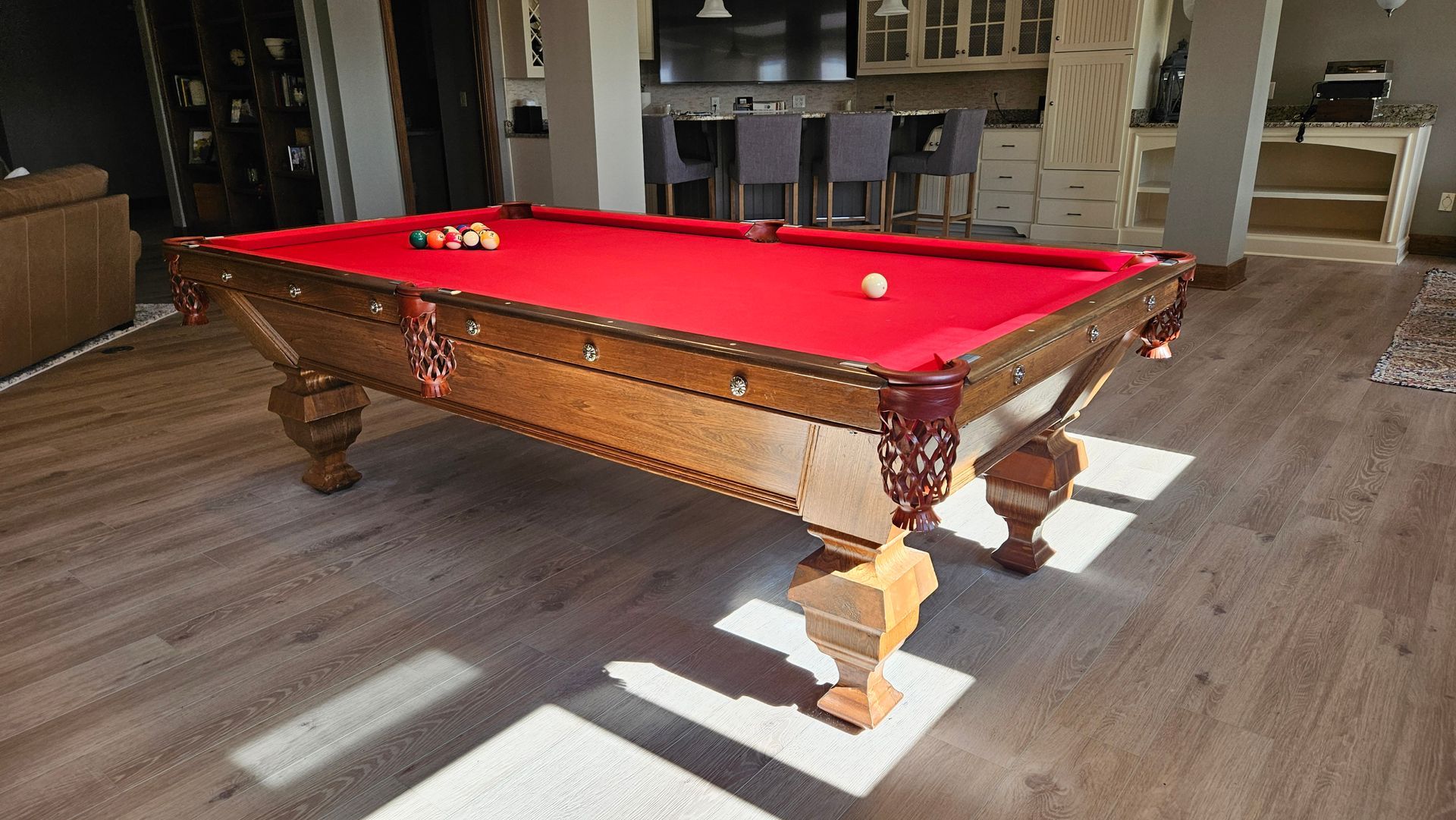 A pool table in a living room with a red cloth