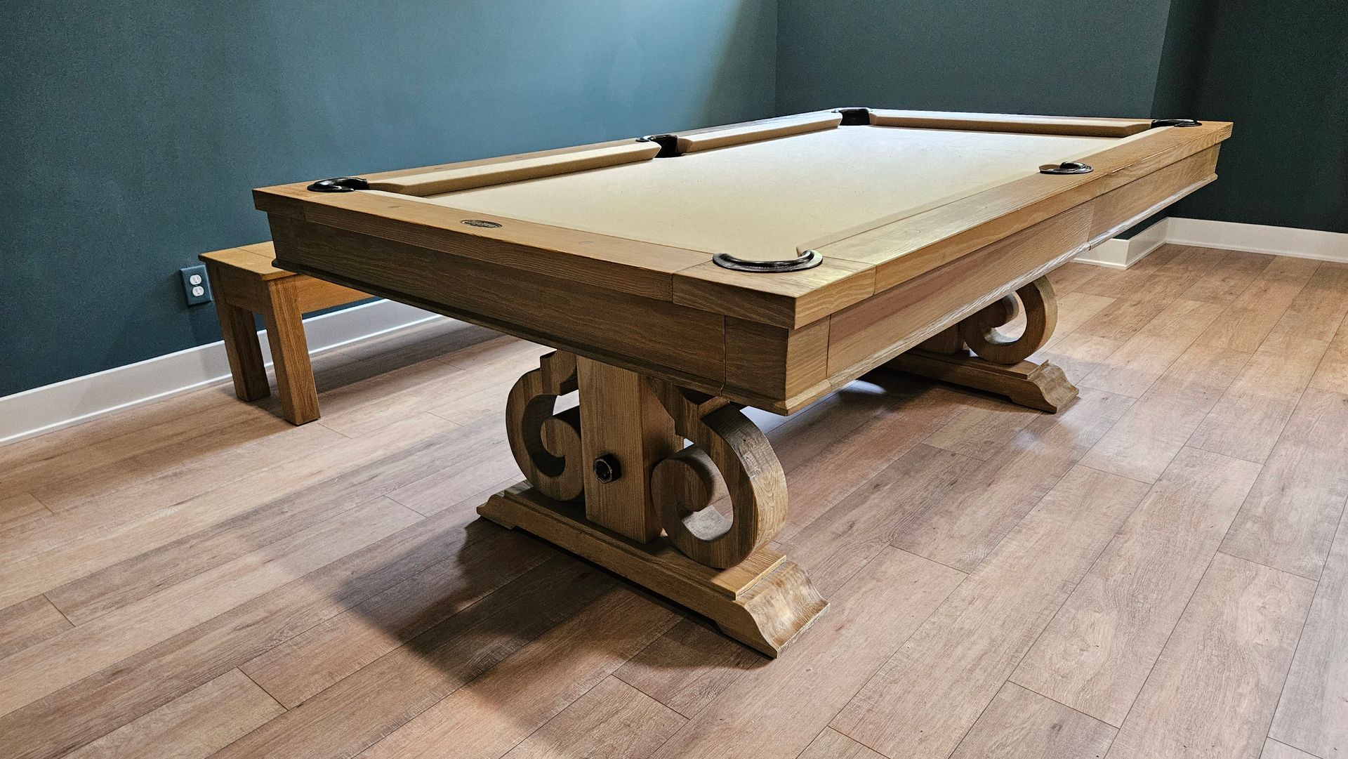 A pool table is sitting on a wooden floor in a room.