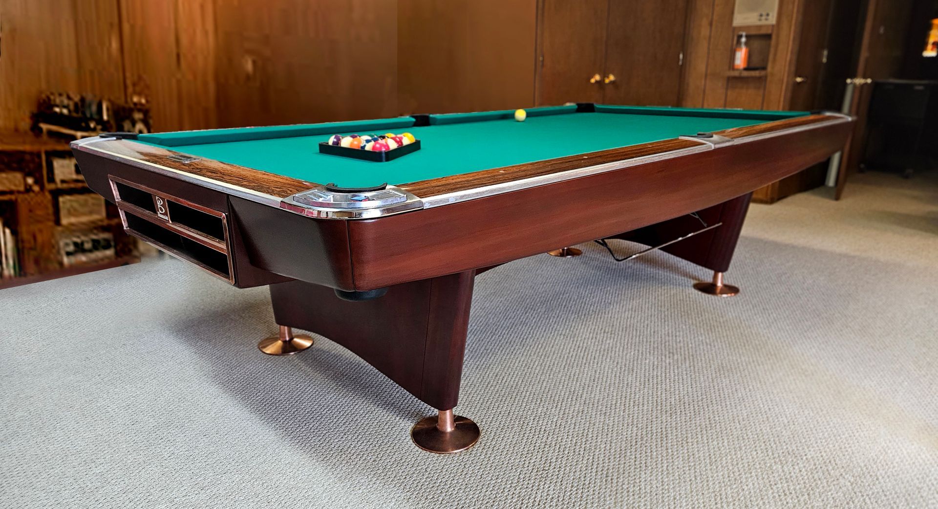 A pool table is sitting on a carpeted floor in a room.